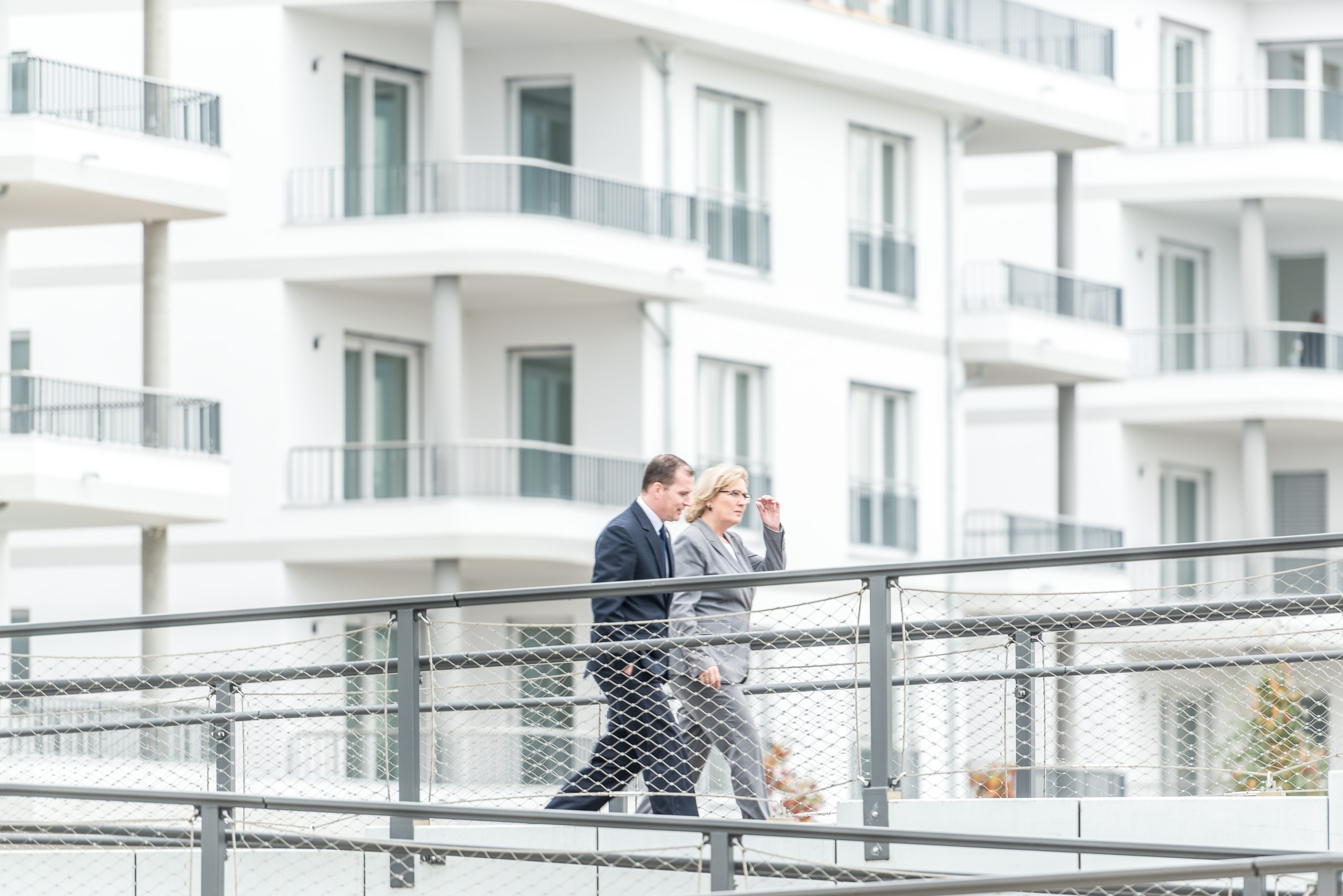 Zwei Personen gehen über eine Brücke im modernen Neubauquartier Havelauen in Werder (Havel). Es handelt sich um Bürgermeisterin Saß und ihren Beigeordneten Große.